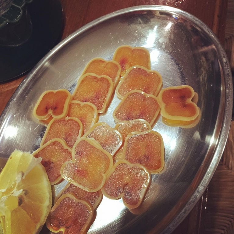 dry slices of avgotaraho with lemon on the aluminum plateau from Bottarga Stefos